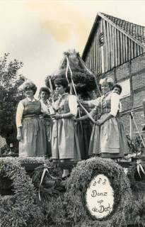 ARH Slg. Bartling 4154, Junge Frauen im Dirndlkleid auf einem geschmückten Wagen die Erntekrone haltend beim Erntefestumzug, im Hintergrund ein Fachwerkgiebel, Empede, um 1970