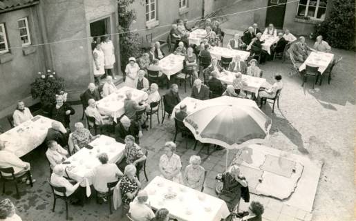 ARH Slg. Bartling 4214, Kaffeetrinken der Bewohner an weiß gedeckten Tischen im Hof des Kreisaltersheims, Hagen, 1974