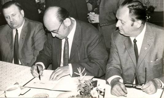 ARH Slg. Bartling 4250, Unterzeichnung des Grenzänderungsvertrages zwischen Helstorf und Abbensen (?), drei Männer am Tisch sitzend beim Unterschreiben, Helstorf, 1971