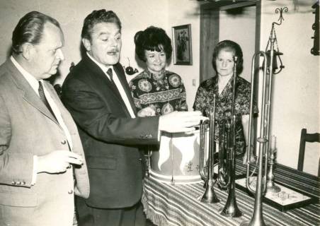 ARH Slg. Bartling 4273, Bürgermeister Herbert Kluth (l.) und Frau Else (r.) zu Gast bei Rudolf und Sabina Gast beim Studium der im Hause ausgestellten Instrumente des Fanfarenzugs, Helstorf, 1970