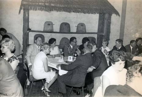ARH Slg. Bartling 4376, Standortball im Soldatenheim Haus an der Jürse, Blick auf Tisch Nr. 5 mit zivilen und uniformierten Festteilnehmern vor einem Wandregal mit Bienenkörben, Luttmersen, um 1975