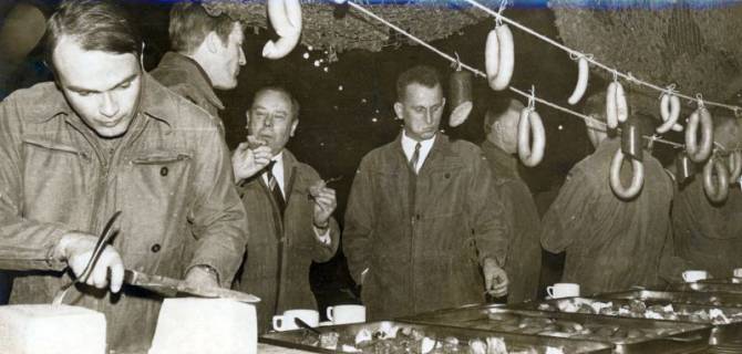 ARH Slg. Bartling 4382, Abendliches Biwak auf einer Barbarafeier, Gäste beim Essenfassen, Blick über das Büffet mit aufgehängten Würsten, Luttmersen, 1968