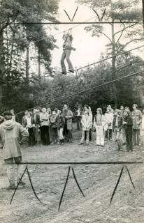 ARH Slg. Bartling 4387, Tag der offenen Tür, ein (angeseilter) junger Mann beim Gehen auf einem zwischen Bäumen gespannten Seil, Blick über den aufsichtführenden Soldaten auf das Seil und die darunter stehenden Beobachter, Luttmersen, 1974