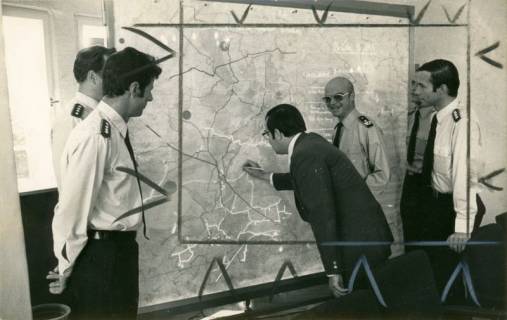 ARH Slg. Bartling 4417, Offiziere des Standortes Luttmersen mit Kreisdirektor Wolfgang Kunze an einer Wandkarte, in der er einen Punkt markiert, rechts daneben der Bataillonskommandeur OTL Stammel, um 1970