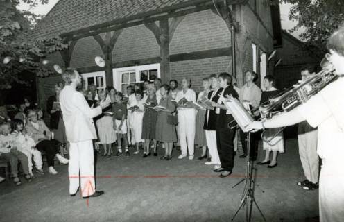 ARH Slg. Bartling 4526, Auftritt des Konzertchors Hannover-Land (unter der Leitung von Claus-Ulrich Heinke) und einer Bläsergruppe der Kreisvolkshochschule bei einem abendlichen Konzert auf dem Aloys-Bunge-Platz, Mardorf, um 1975
