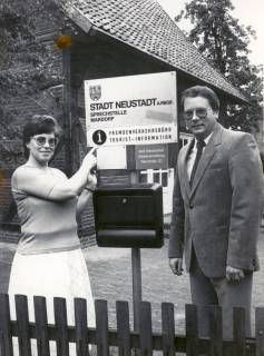 ARH Slg. Bartling 4529, Angestellte Helga Rübenhaus aus dem Büro und Christian Herr, damals 1. Vorsitzender des Verkehrsvereins, neben dem Firmenschild der Sprechstelle des Fremdenverkehrsbüro - Tourist-Information, Mardorf, um 1980