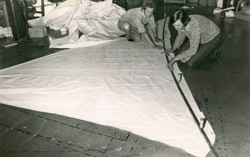ARH Slg. Bartling 4538, Zwei Männer beim Zuschnitt eines Segeltuchs auf dem Boden in der Segelmacherei Jörg Hustau, Mardorf, um 1980