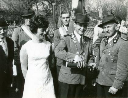 ARH Slg. Bartling 4647, Schützenkönig stehend mit Flasche in der Hand, neben und hinter ihm uniformierte bzw. chargierte Schützenbrüder, links eine Dame in weißem Kleid beim Schützenfest, Metel, 1970