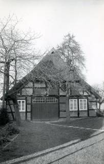 ARH Slg. Bartling 4673, Bauernhaus, Fachwerkbau mit Krüppelwalmdach, Strohdach, Giebelansicht mit Rasen-bedecktem Vorhof, Zuwegung über Waschbetonplatten, Niedernstöcken, um 1975