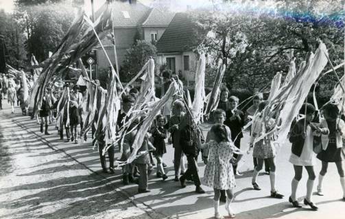 ARH Slg. Bartling 4704, Umzug mit einer Gruppe von Kindern, die Stangen schwenken, an deren Spitzen bunte Streifenbüschel befestigt sind beim Schützenfest, Nöpke, 1970