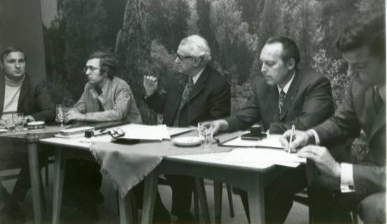 ARH Slg. Bartling 4762, Fünf Männer in einem Saal hinter einem Tisch vor Waldtapete sitzend, Otternhagen, 1972