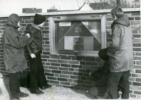ARH Slg. Bartling 4789, Begutachtung des neuen Aushangkastens an der Kirchenmauer durch vier Jungen, Otternhagen, 1970