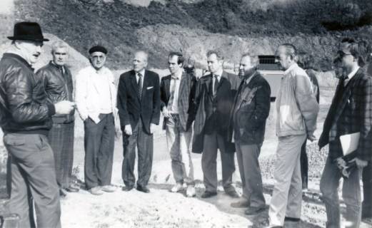 ARH Slg. Bartling 4897, Blick auf die nebeneinander stehenden Ratsleute in der Kiesgrube, die dem Vortrag eines Mannes mit Hut zuhören, Scharrel, um 1975