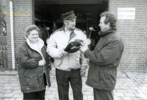 ARH Slg. Bartling 4919, Überreichung einer Schirmmütze an N. N. (mit Frau) durch N. N. vor dem Feuerwehrgerätehaus, Borstel, um 1980