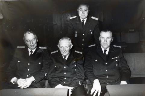 ARH Slg. Bartling 4941, Gruppenfoto der mit Ehrenurkunden ausgezeichneten vier älteren uniformierten Feuerwehrleute (drei sitzend, dahinter in der 2.Reihe stehend Horst Liem), um 1975
