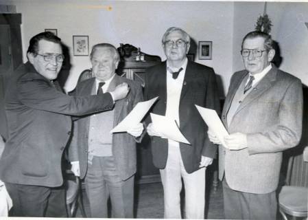 ARH Slg. Bartling 5004, Überreichung einer Ehrenurkunde an drei nebeneinander stehende ältere Herren (2. v. r. Heinz Vehrenkamp) durch N. N. (l.) in einem Wohnzimmer, Wulfelade, um 1980