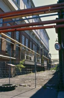 ARH Slg. Bürgerbüro 13, Blick durch den Zaun auf das Gebäude der ehemaligen Hanomag Maschinenbau AG, Linden, 1999