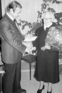 ARH Slg. Weber 02-018/0018, Ein Mann überreicht einer älteren Dame einen Blumenstrauß und eine Urkunde, zwischen 1980/1990