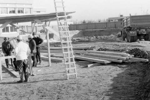 ARH Slg. Weber 02-022/0015, Bauarbeiter stehen auf einer Baustelle unter einem Baugerüst vor der Haupt- und Realschule, Gehrden, zwischen 1980/1990