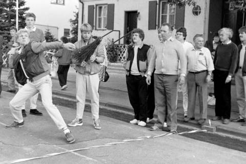 ARH Slg. Weber 02-032/0005, Ein Mann beim Rutenweitwurf vor der Alten Schule/Dorfgemeinschaftshaus während des Straßenfest in Lenthe, zwischen 1980/1990