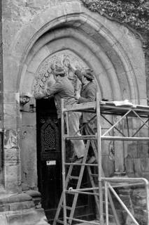 ARH Slg. Weber 02-037/0001, Zwei Männer reinigen das Kirchenportal der Margarethenkirche, Gehrden, zwischen 1980/1990