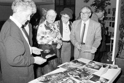 ARH Slg. Weber 02-045/0017, Mehrere Personen an einem Tisch mit Fotografien bei einer Ausstellung zum Filmtheater und dem ersten Filmabend im Nostalgiekino im Bürgersaal des Rathauses, Gehrden, 1996