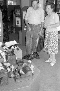 ARH Slg. Weber 02-053/0009, Ein älteres Ehepaar mit ihrem Dackel bei einer Ausstellung in der Geschäftsstelle der Volksbank, Gehrden, zwischen 1980/1990