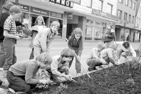 ARH Slg. Weber 02-081/0011, Kinder und Erwachsene bei der Neubepflanzung eines Blumenbeets an der Dammstraße, Gehrden, zwischen 1980/1990