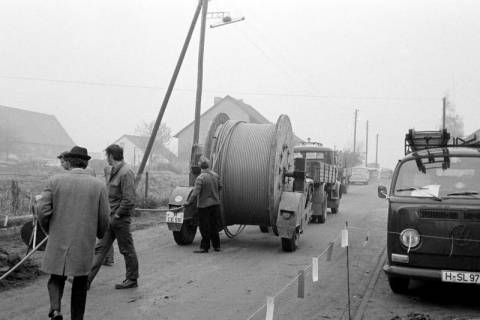 ARH Slg. Weber 02-086/0006, Männer verlegen neben einer Straße Kabel mithilfe einer Kabeltrommel, zwischen 1970/1980