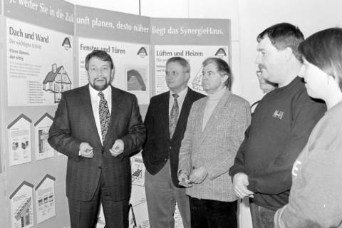 ARH Slg. Weber 02-087/0007, Betriebsleiter der Avacon Gehrden Detlev Wackenrohr (links) und weitere Personen vor einer Ausstellung zum Thema "SynergieHaus", Gehrden, zwischen 1980/1990