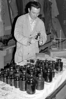ARH Slg. Weber 02-087/0014, Ein Kontrolleur vom Eichamt mit Gewichtsstücken in einer Werkstatt, zwischen 1970/1980