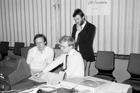 ARH Slg. Weber 02-128/0002, V.l. N.N. und und Heinz Mensing von EDV Rath&Mensing an einem Computer zur Vorführung von CAD-Anwendungen mit Reiner Rath (stehend), zwischen 1980/1990