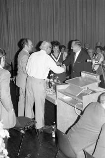 ARH Slg. Weber 02-128/0006, Zwei Männer geben sich die Hand bei einer Veranstaltung in einem Saal, zwischen 1980/1990