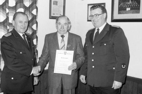 ARH Slg. Weber 02-128/0019, Zwei Mitglieder der Feuerwehr stehen neben einem Mann mit einem Besitzzeugnis, zwischen 1980/1990