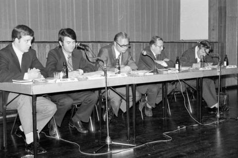 ARH Slg. Weber 02-135/0018, Mehrere Männer nebeneinander an einem Tisch vor einer Bühne, zwischen 1980/1990