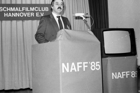 ARH Slg. Weber 02-143/0005, Ein Mann hält an einem Podium eine Rede bei einem Treffen des Schmalfilmclubs Hannover e.V., 1985