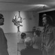 Archiv der Region Hannover, ARH NL Mellin 01-124/0009, Unterhaltung zweier Männer vor sitzenden Menschen und einem Kunstwerk?