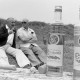 Archiv der Region Hannover, ARH NL Mellin 01-133/0013, Zwei Flaschen "Troyanska Slivova" (Pflaumenbrand) vor zwei im Gras sitzenden Männern