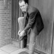 Archiv der Region Hannover, ARH NL Mellin 01-136/0011, Mann bindet sich im Stehen den Schuh vor einer Haustür