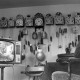 ARH NL Mellin 01-146/0017, Mehrere Pendeluhren an einer Wand und ein Junge vor einem Fernseher