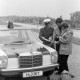 Archiv der Region Hannover, ARH NL Mellin  01-197/0008, Ein Polizist und zwei Zivilisten neben einem Polizeiwagen stehend und auf eine Karte schauend