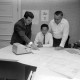 Archiv der Region Hannover, ARH NL Mellin 01-200/0017, Drei Männer in der Besprechung über auf einem Tisch verteilte Dokumente in einem Büro