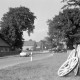 ARH NL Mellin 02-065/0002, Blick auf eine Straße in einem Dorf, rechts drei Wagenräder am Straßenrand