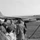 ARH NL Mellin 02-077/0016, Gruppe von Menschen an einem Flughafen, im Hintergrund ein Flugzeug (Typ "Douglas DC-8") der Frachtfluggesellschaft "Airlift International"