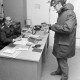 Archiv der Region Hannover, ARH NL Mellin 02-079/0019, Junger Mann bei einem Polizisten in einem Büro der Polizeiwache stehend