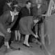 Archiv der Region Hannover, ARH NL Mellin 02-173/0006, Frau beim Radwechsel an einem Auto vor einem Publikum