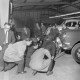 Archiv der Region Hannover, ARH NL Mellin 02-173/0012, Gruppe von Personen betrachtet ein aufgebocktes Auto in einer Autowerkstatt