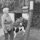 ARH Slg. Bartling 1052, Frau im Spätsommer mit geflecktem Hund steht vor dem Apfelbaum am Eingang des Hauses Apfelallee 23 und liest die am Baumstamm befestigte amtliche Bekanntmachung, Neustadt a. Rbge.