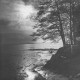 ARH Slg. Bartling 1157, Abendstimmung am winterlichen Nordufer, Blick durch die entlaubten Bäume am Ufer auf den zugefrorenen See und die hinter den Wolken verschwindende Sonne, Steinhuder Meer