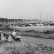 Stadtarchiv Neustadt a. Rbge., ARH Slg. Bartling 1214, Nordufer, Blick über eine Sitzbank (links) am Uferweg auf Bootsanleger in der Nähe des Kurhotels (Seehotels?) mit zahlreichen Booten, Steinhuder Meer